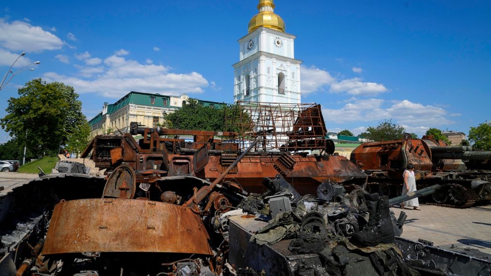 A woman looks at a destroyed Russian tanks installed as a symbol of war in central Kyiv, Ukraine, Tuesday, June 7, 2022. St Michael cathedral is in the background. (AP Photo/Efrem Lukatsky)