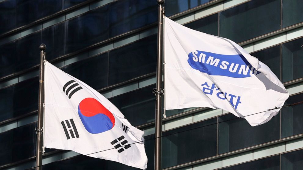 FILE - The company flag of Samsung Electronics, right, flutters next to the South Korean national flag in Seoul, South Korea, on Jan. 16, 2017. Samsung Electronics is shifting away from fossil fuels and aiming to entirely power its global operations
